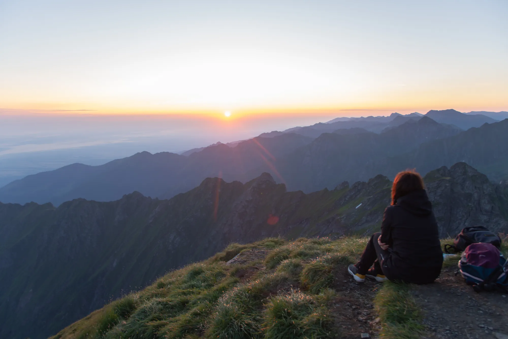 Sunrise over the Făgăraș ridge, a walker resting on the crest