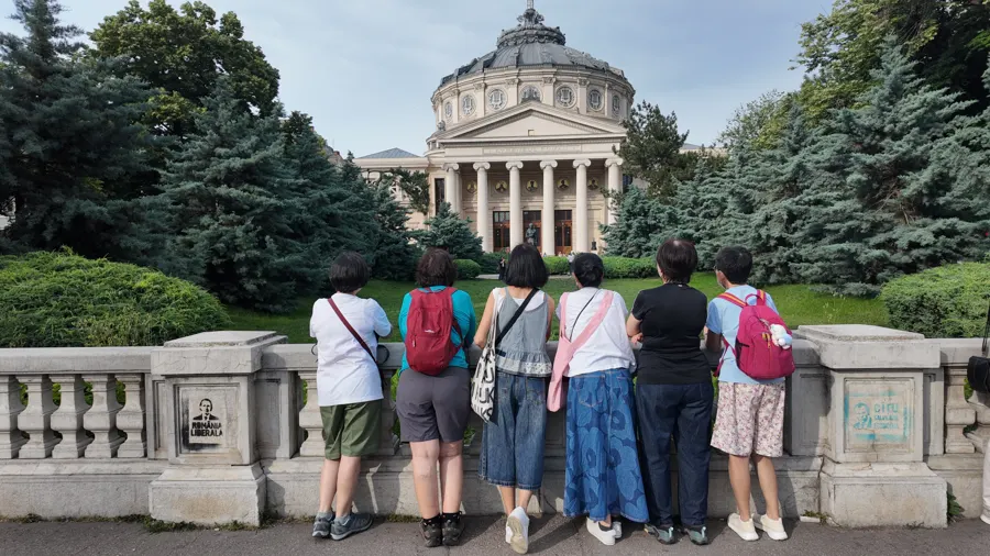 Travellers looking at the Romanian Athenaeum in Bucharest, seen from behind