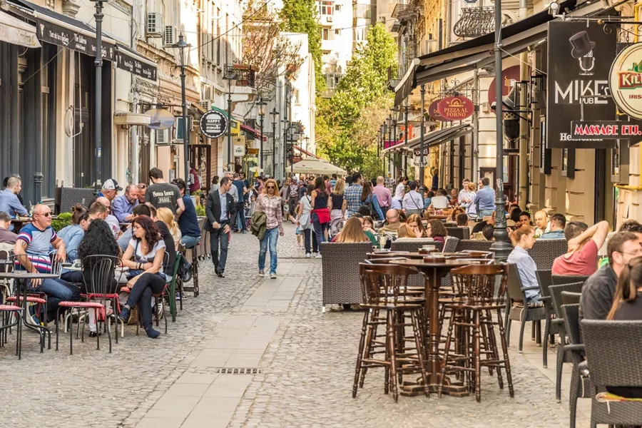 People at café tables on a pedestrian street in the Old Town of Bucharest