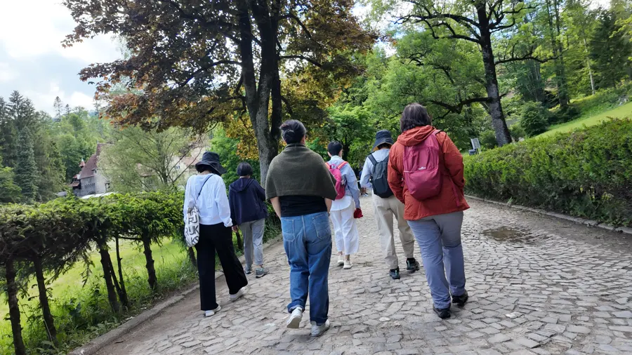 Travellers walking along a garden path at Peleș Castle in Sinaia
